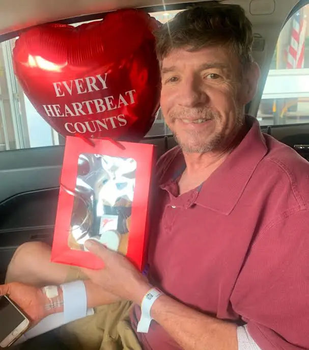 Man holding a red heart-shaped balloon and a photo frame.