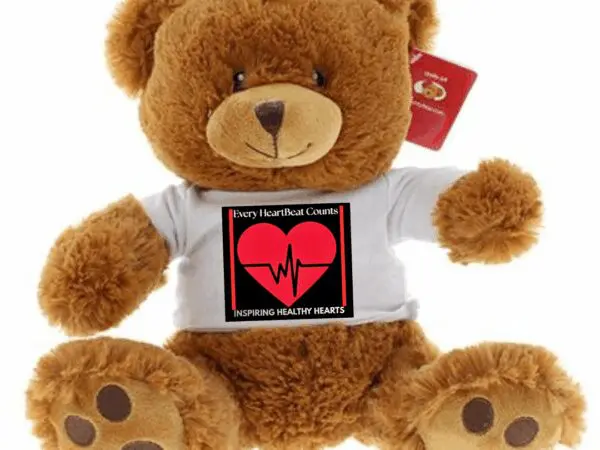 A brown teddy bear wearing a white shirt with a heart and heartbeat design.
