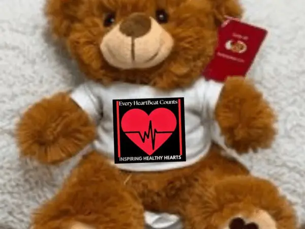 A teddy bear holding a heart-themed sign about love and life.