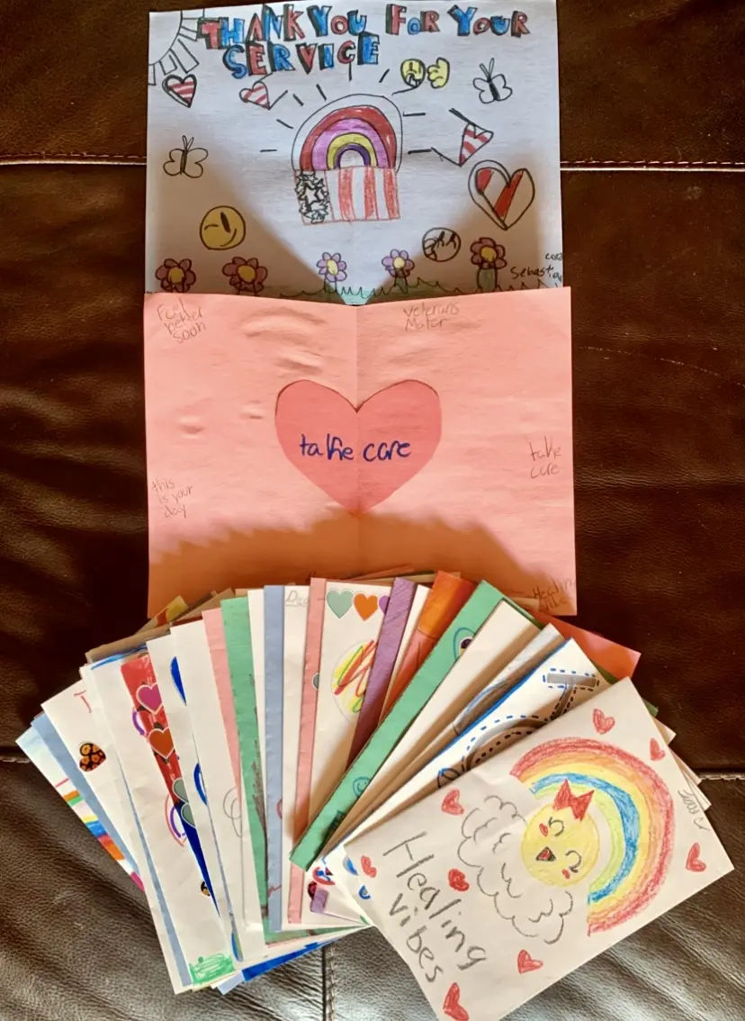 A collection of colorful, decorated cards with a pink gift bag.