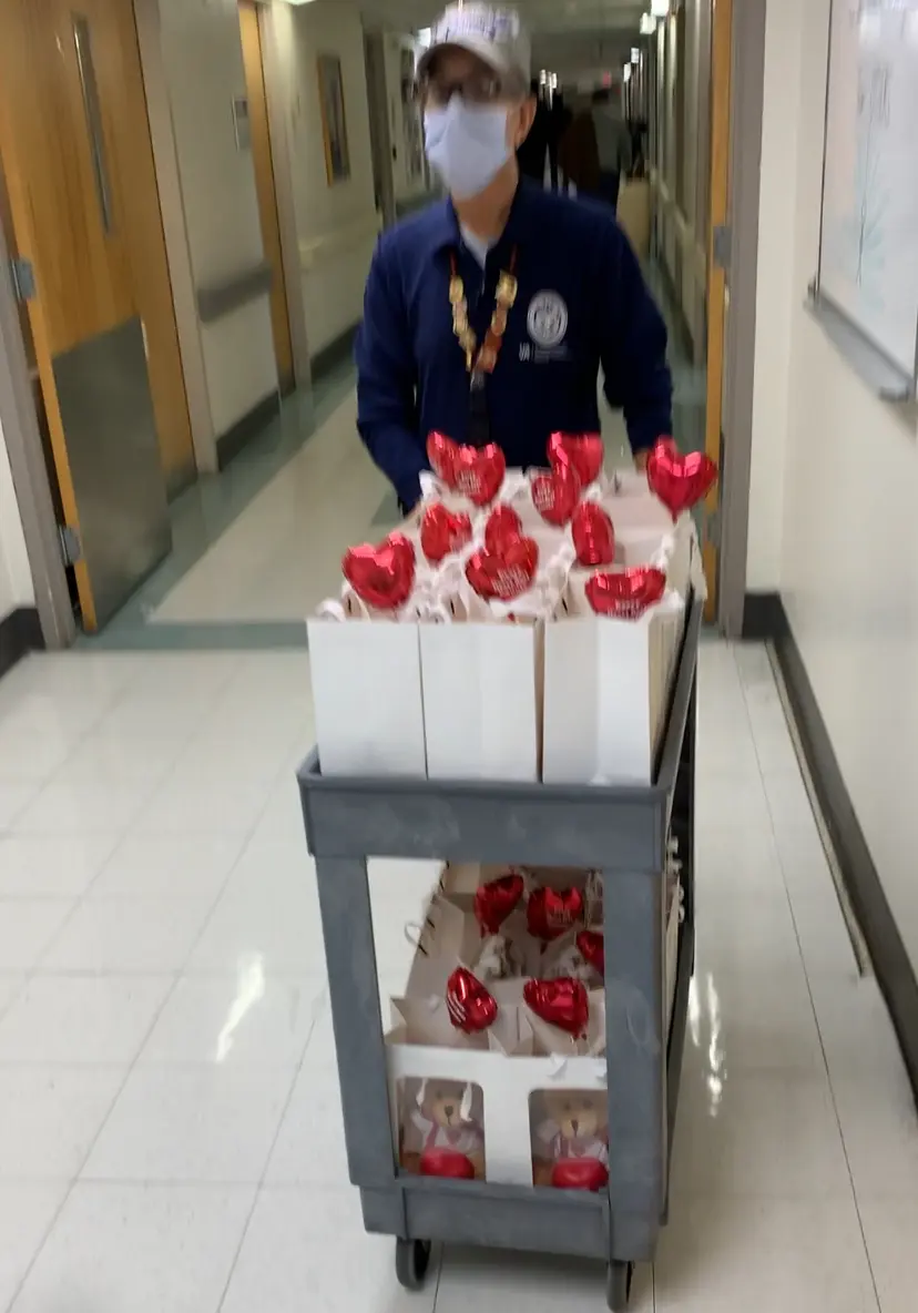 Person pushing a cart with white boxes and red heart decorations in a hallway.