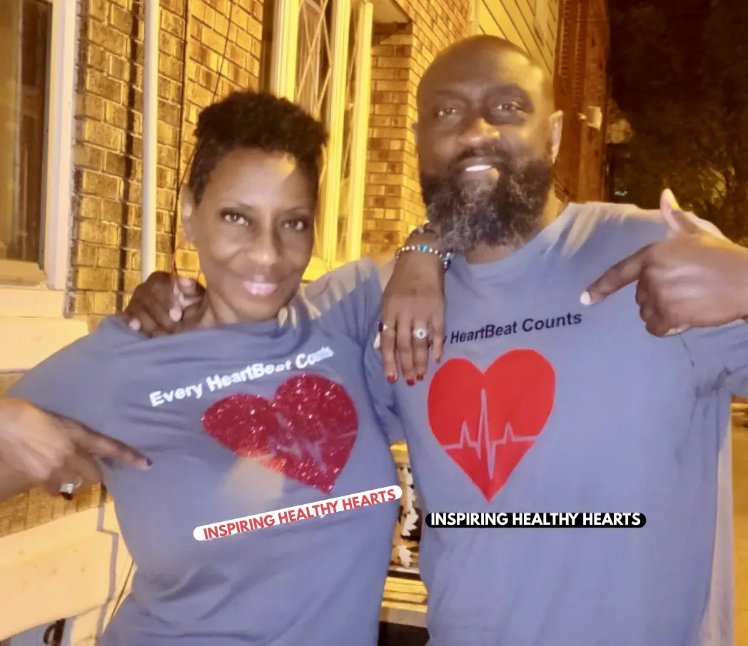 Two people smiling and wearing matching heart-themed shirts.