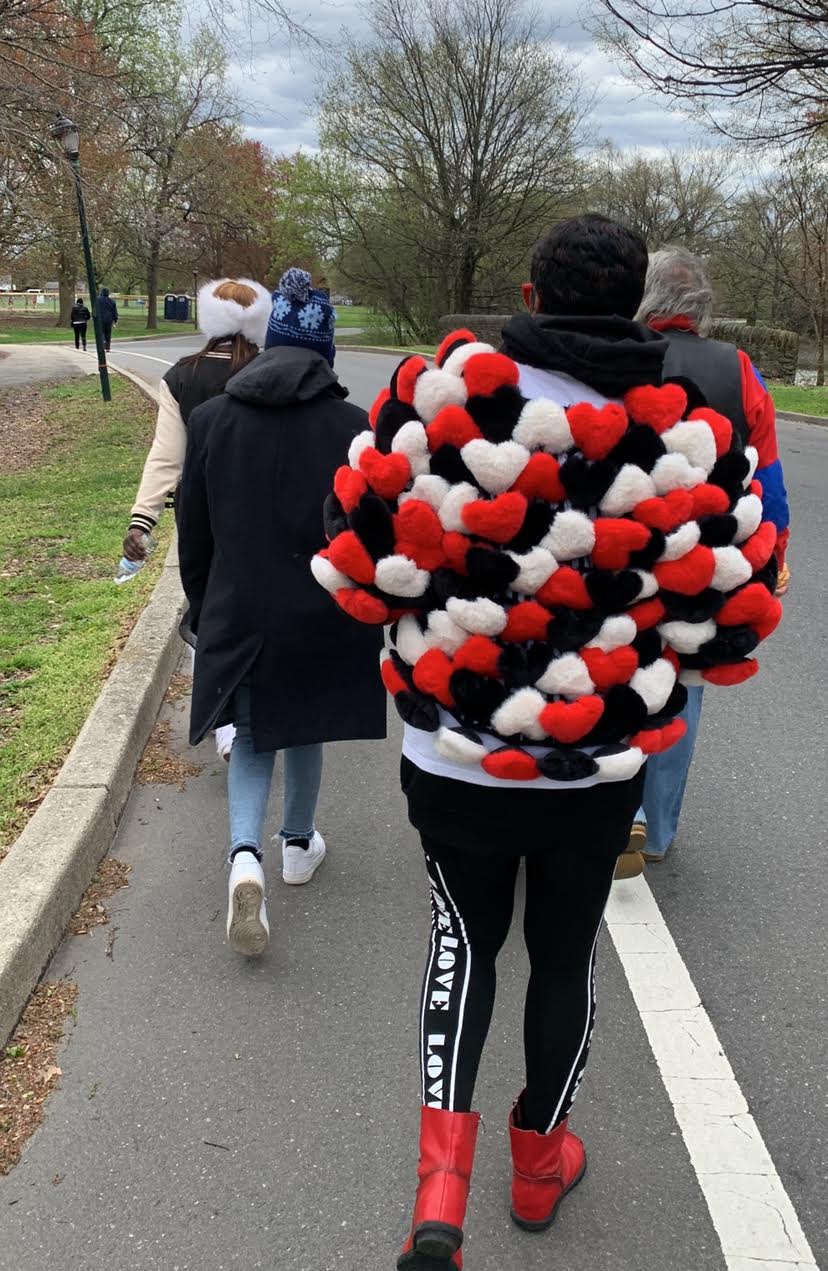 Person wearing a bold, red, black, and white patterned jacket walking outdoors.